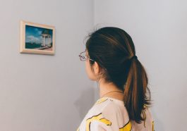 mujer en una galería de arte, observando un cuadro.